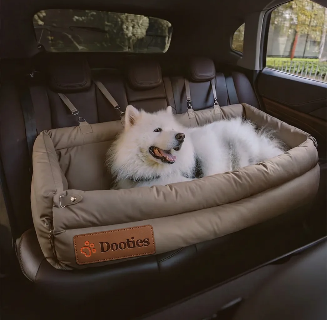 Samoyed resting in khaki dog car seat in back of car