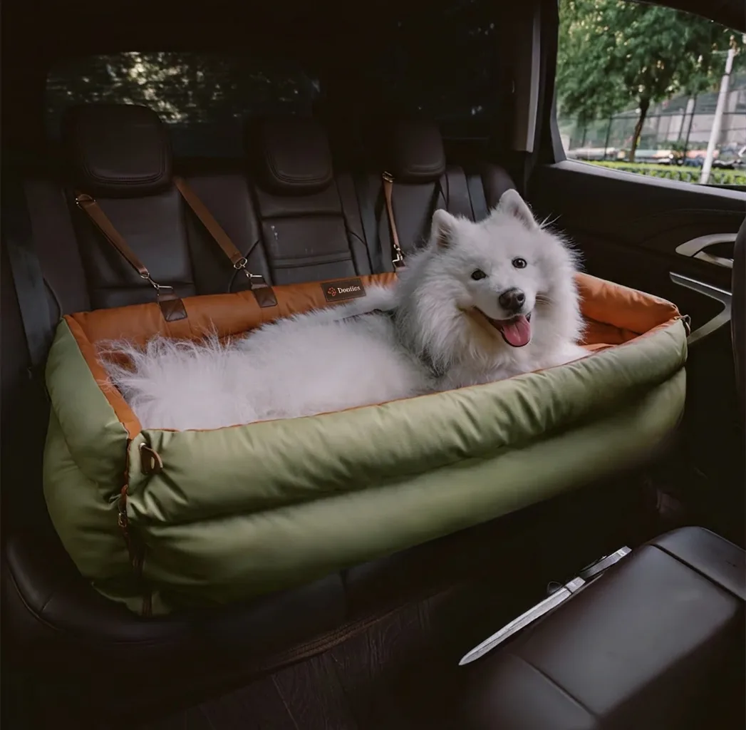 Samoyed lying in orange and green dog car seat
